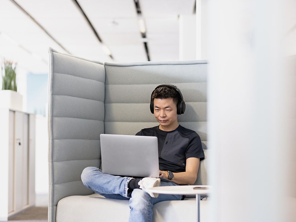 En Henkel-anställd med hörlurar arbetar koncentrerat på sin bärbara dator. 