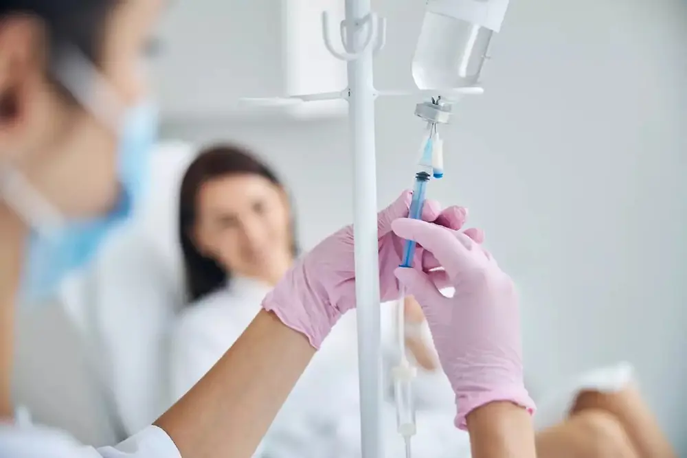 Sjukvårdspersonal håller en infusionspåse i en vårdmiljö.